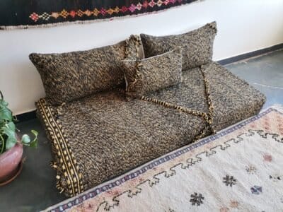 Left view of handwoven Moroccan floor couch in black and mustard – perfect for edgy, warm-toned home styling