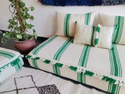 Right view of handmade Moroccan floor sofa with green lines and decorative pom-poms – artisan wool couch for fun bohemian homes