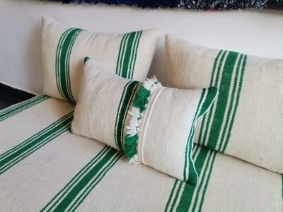 Moroccan sofa in cream with green stripes and pom-pom detail – artisan wool pillows for joyful boho decor