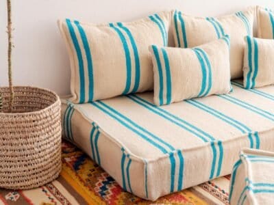 Left side image of Moroccan floor seating with turquoise striped pattern on cream – handmade wool low sofa