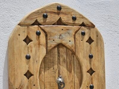Upper section of arched Moroccan wooden panel showing curved detailing and metal studs