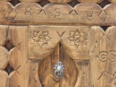 Moroccan wooden wall decor featuring a metal door knocker and detailed star-shaped tribal carvings