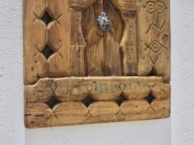 bottom section of a vintage Moroccan wood panel showing aged surface and hand-carved motifs