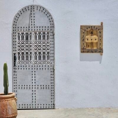 Outdoor installation view of Moroccan shutter beside traditional white door