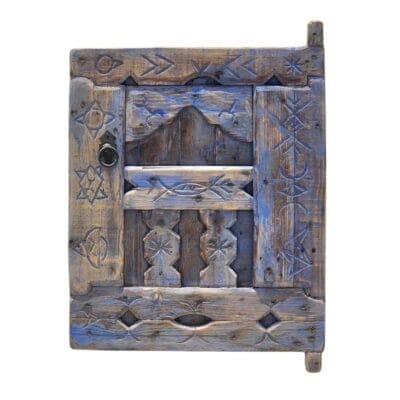 Vintage Moroccan blue shutter window with Berber carvings on white wall