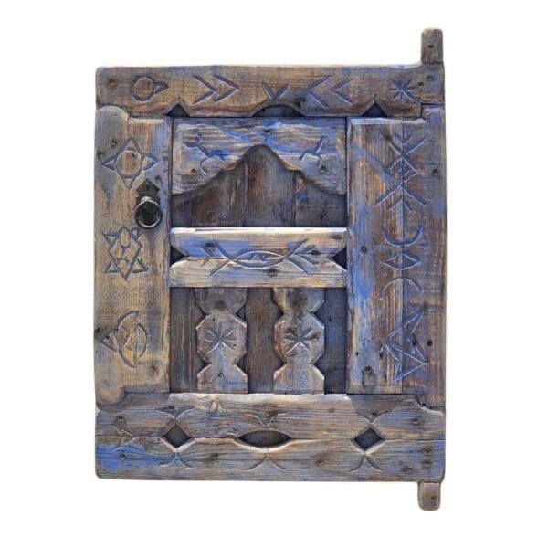 Vintage Moroccan blue shutter window with Berber carvings on white wall