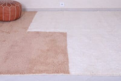 corner of handmade Moroccan rug in ivory and tan, revealing rug thickness and high-quality construction.