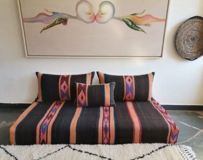 Stacked wool pillow covers in black, orange, and blue embroidery