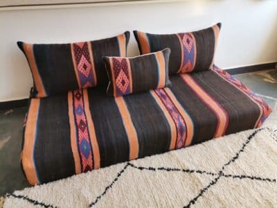 Boho-style room with black and orange Moroccan floor seating with blue stripes