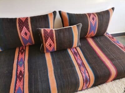 Side view of black and orange Moroccan floor cushion with visible embroidered stripe