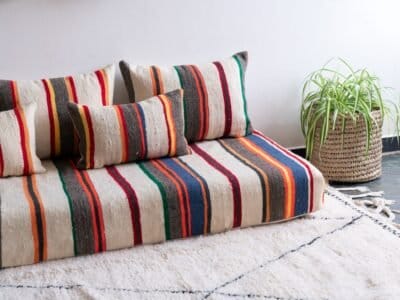 Moroccan floor seating arrangement with ivory lamb wool cushions and vibrant stripes