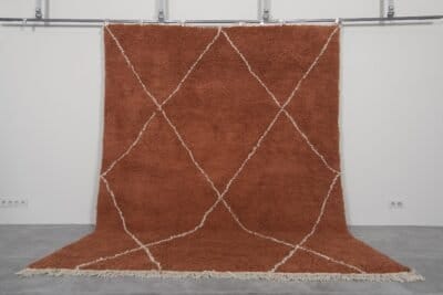 Handmade Moroccan rug with a warm terracotta background and soft ivory trellis pattern, woven by Berber artisans using 100% natural lamb wool in the classic Beni Ourain style.