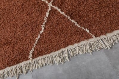 fringe and finishing detail on terracotta and ivory Moroccan rug, emphasizing handmade quality and Berber craftsmanship.