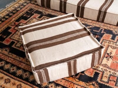 Artisan hand-finishing ivory wool cushion with brown embroidery
